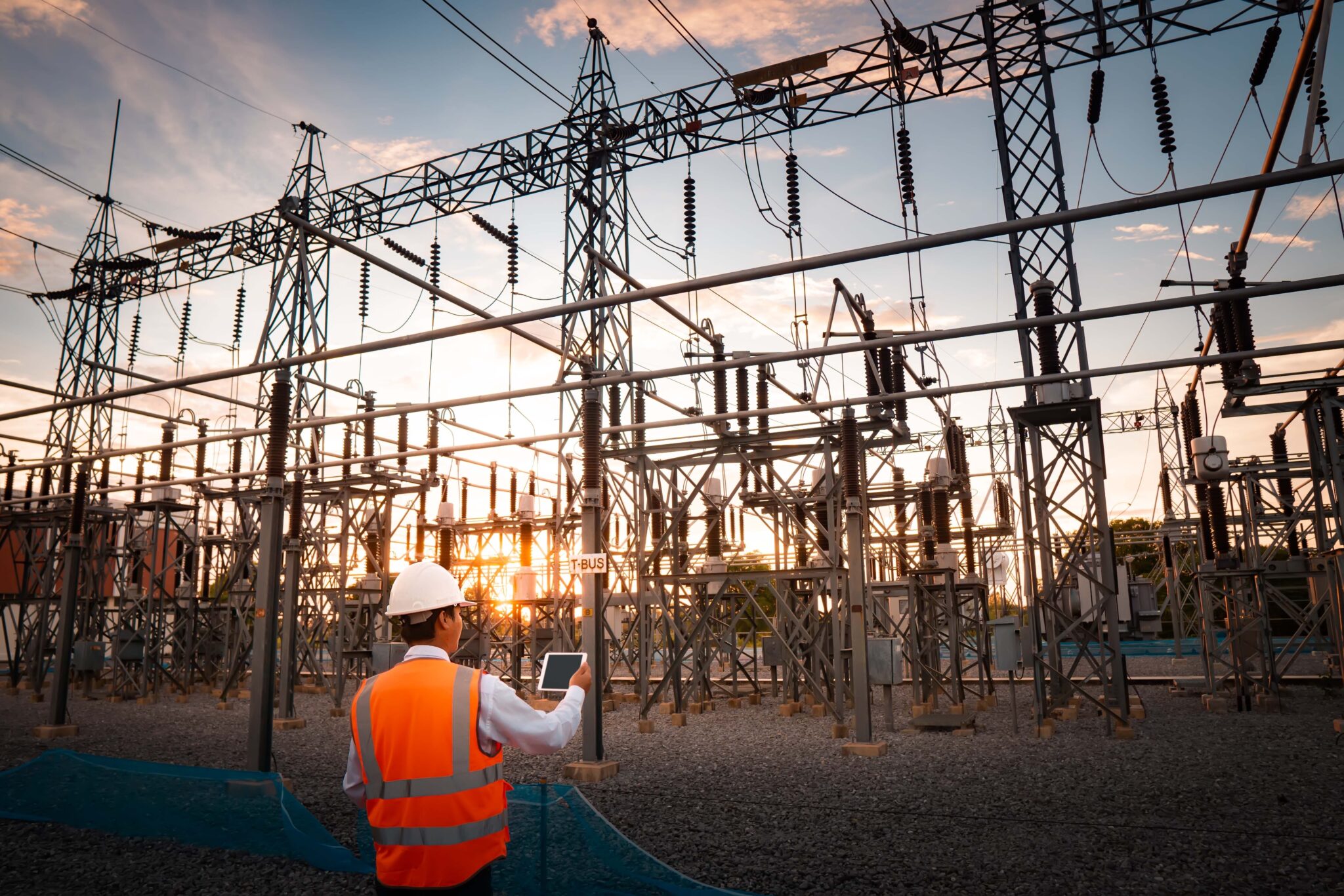 Worker standing in front of large outdoor substation