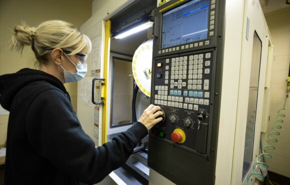 Worker adjusting the control panel of a large prototyping machine