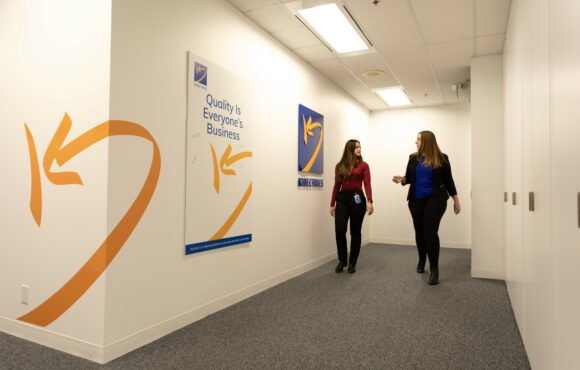 People walking down a corridor with the Kinectrics logo on the wall.