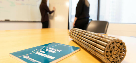 Closeup of a CANDU fuel bundle alongside textbook on a desk