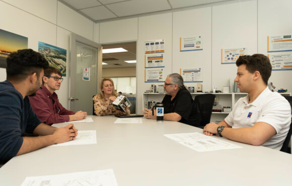 Workers in a boardroom examining machine component