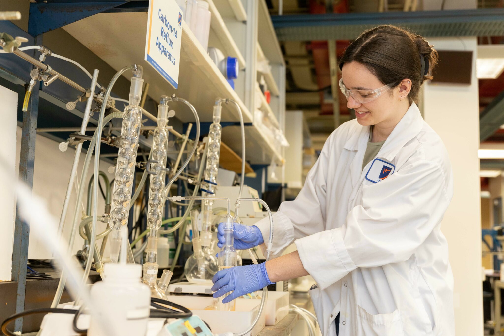 Worker examining beaker mounted into a carbon-14 reflux apparatus