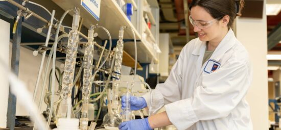 Worker examining beaker mounted into a carbon-14 reflux apparatus
