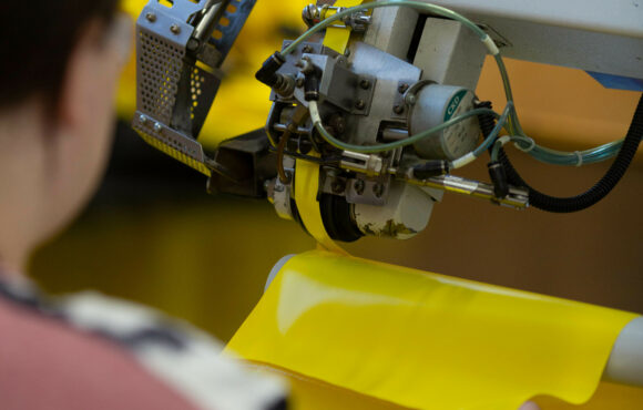 Closeup of worker operating protective suit assembling machine