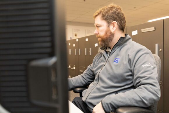 Photo of an engineer working at a computer screen taken from behind the screen