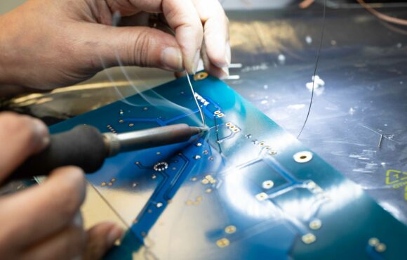 Extreme closeup photograph of worker soldering a circuit board