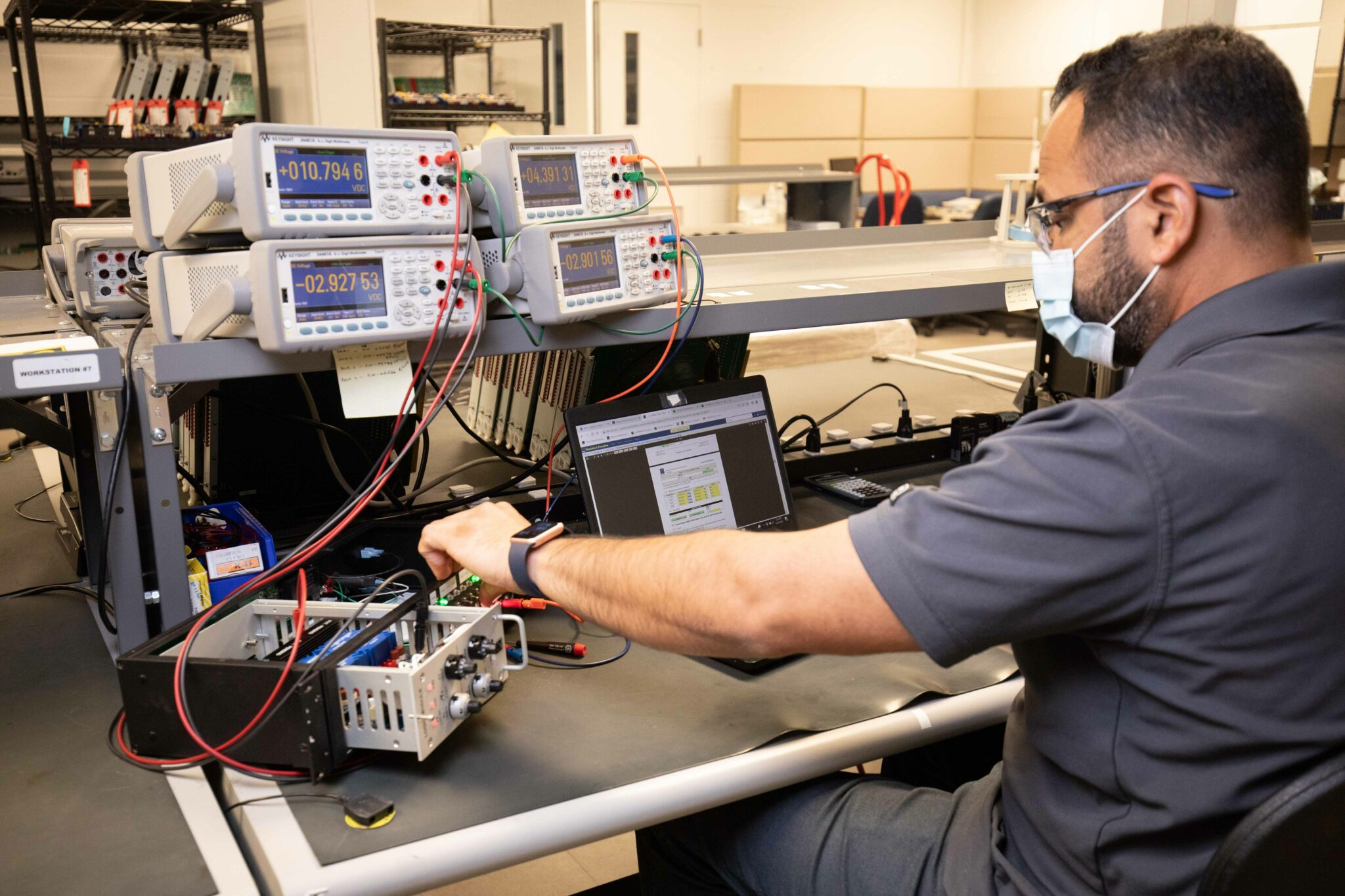 A worker testing machine parts at a work bench