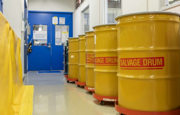 Photograph of a hallway lined with storage drums labelled "Salvage Drum"