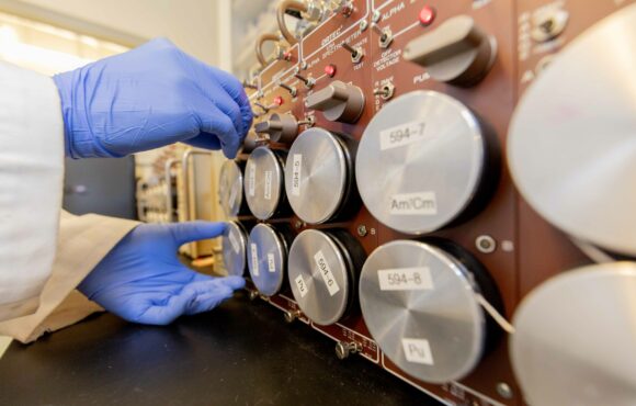 Closeup of worker adjusting dials on an alpha spectrometer