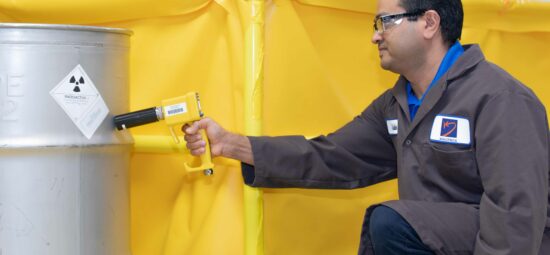 Radiation technician scanning a container filled with radioactive waste material