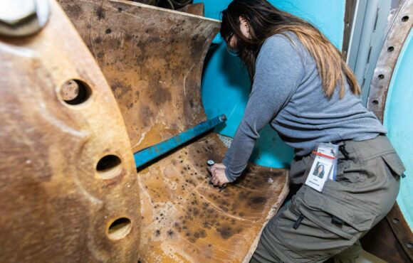 Worker inspecting a large worn pipe
