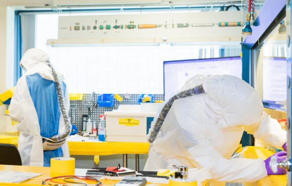 Closeup of workers in protective suits performing maintenance on tools