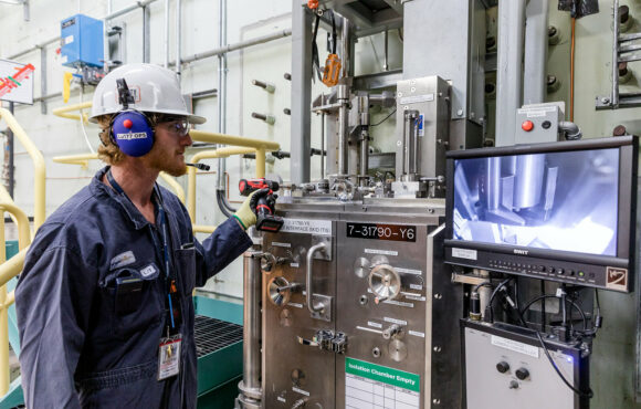 Worker demonstrating the monitoring capabilities of the isotope production system