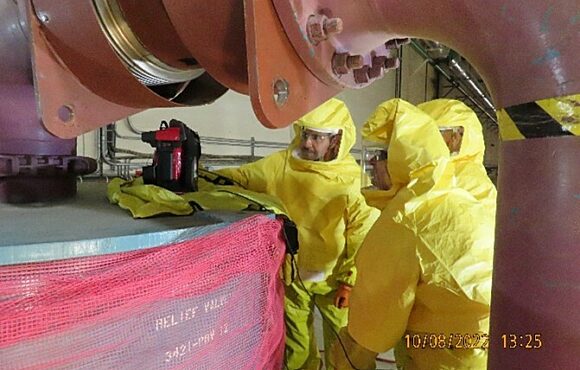 Group of workers inspecting tools while wearing protective suits